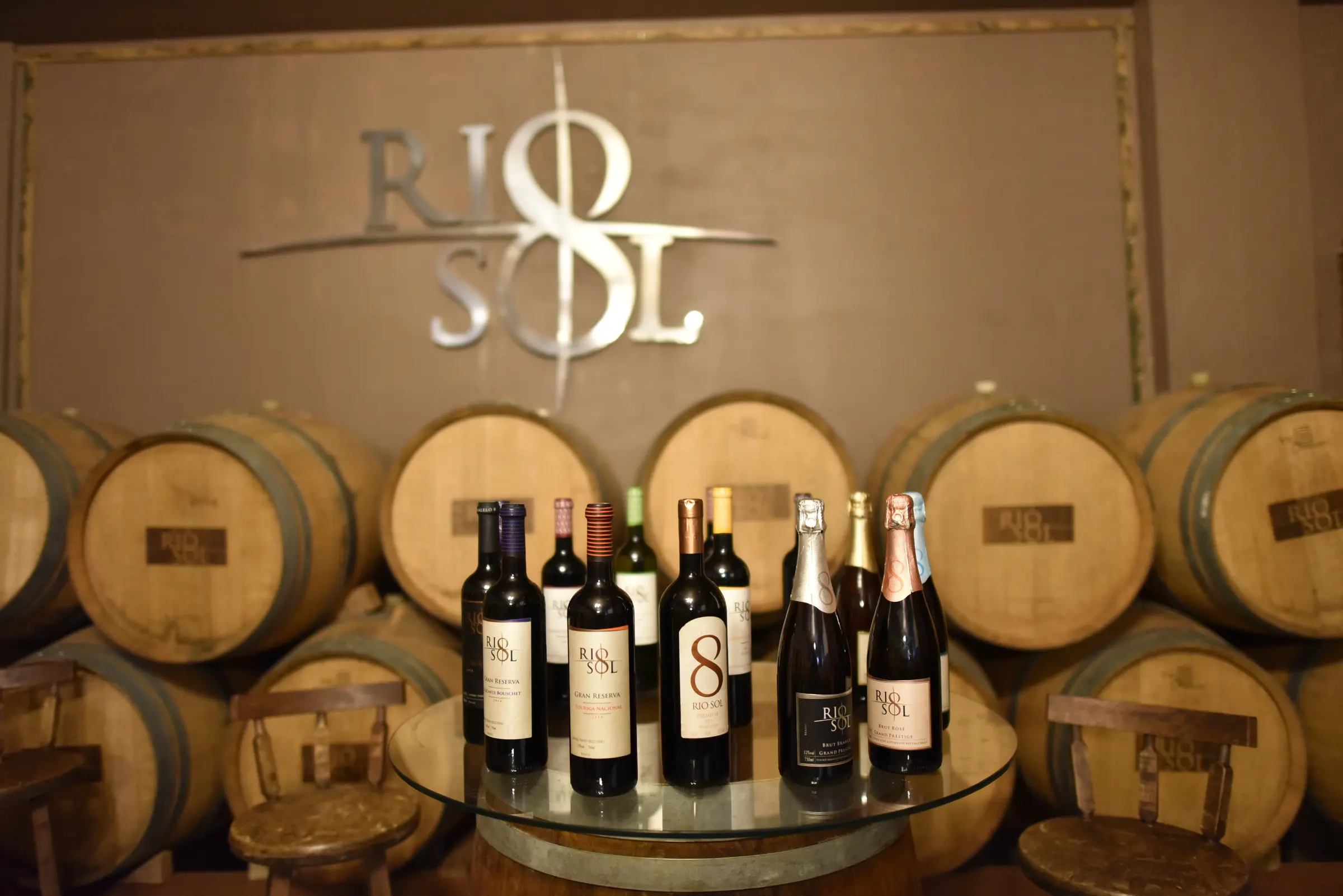 Adega da Vinícola Rio Sol com barris de carvalho e a linha de vinhos e espumantes